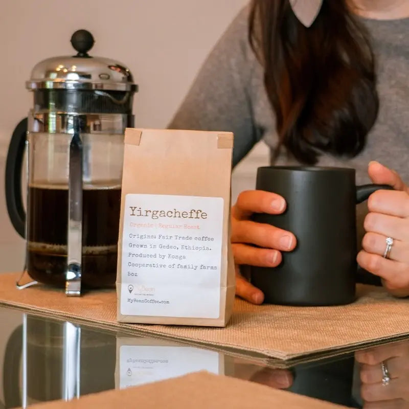 French press coffee alongside bag of coffee and mug